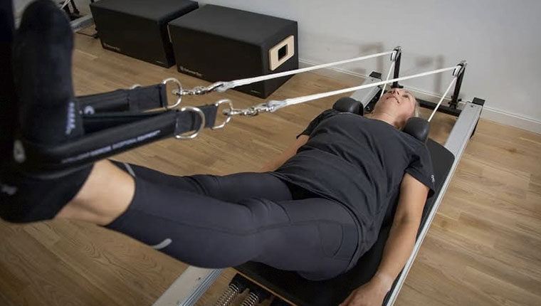 Kvinde træner rygliggende udstrakt i maskine